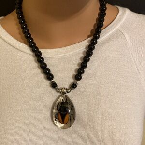 Tear drop resin casted stag beetle pendant on black & silver tone bead necklace